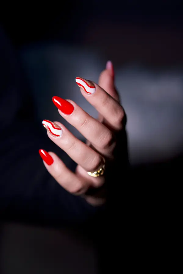 Red swirl nail art on almond-shaped nails