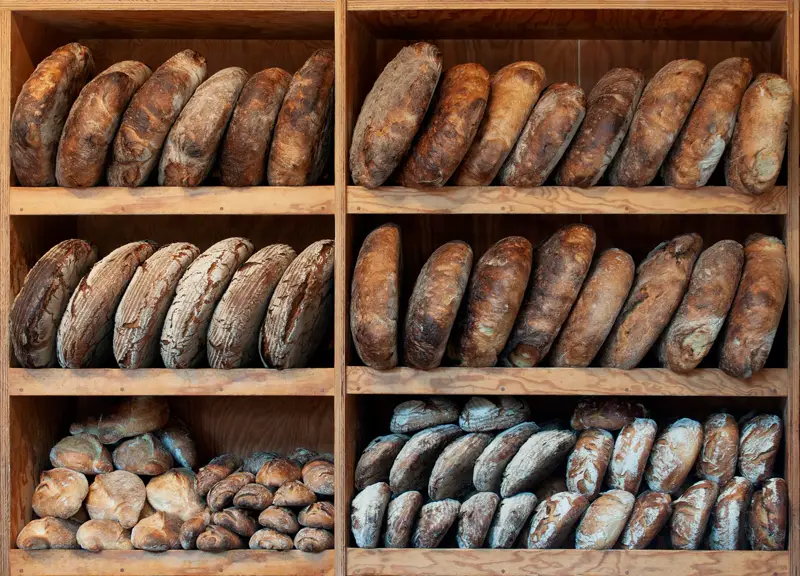 Wooden shelves stacked with crusty sourdough loaves