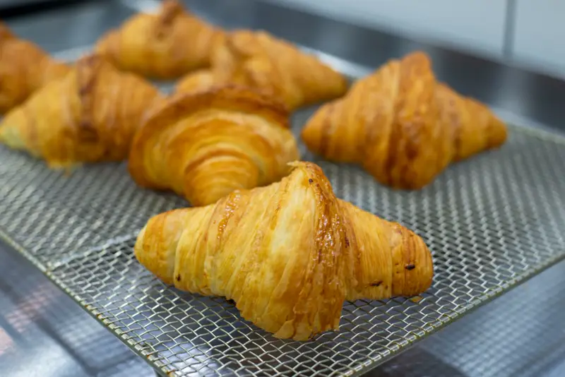 Golden butter croissants cooling on a wire rack